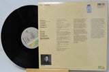 Vinyl record with its cover displaying text and a photo on a light gray background