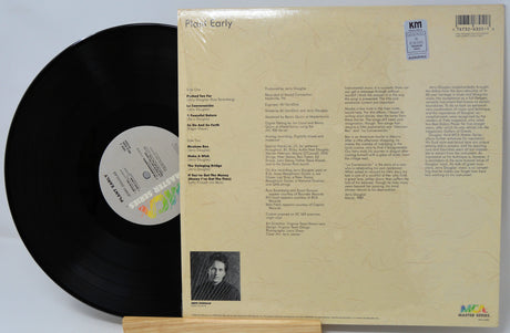 Vinyl record with its cover displaying text and a photo on a light gray background