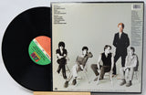 Vinyl record with a cover featuring a band sitting together, on a white background.