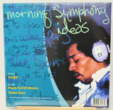 A vinyl record sleeve for Strato Strut's 'Room Full of Mirrors' with handwritten text across the cover, photographed standing on a small wooden display board against a white background.