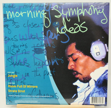 A vinyl record sleeve for Strato Strut's 'Room Full of Mirrors' with handwritten text across the cover, photographed standing on a small wooden display board against a white background.