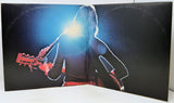 A vintage vinyl record sleeve or album cover displayed open, featuring a silhouetted figure playing an electric guitar against a dark background with a bright spotlight effect.