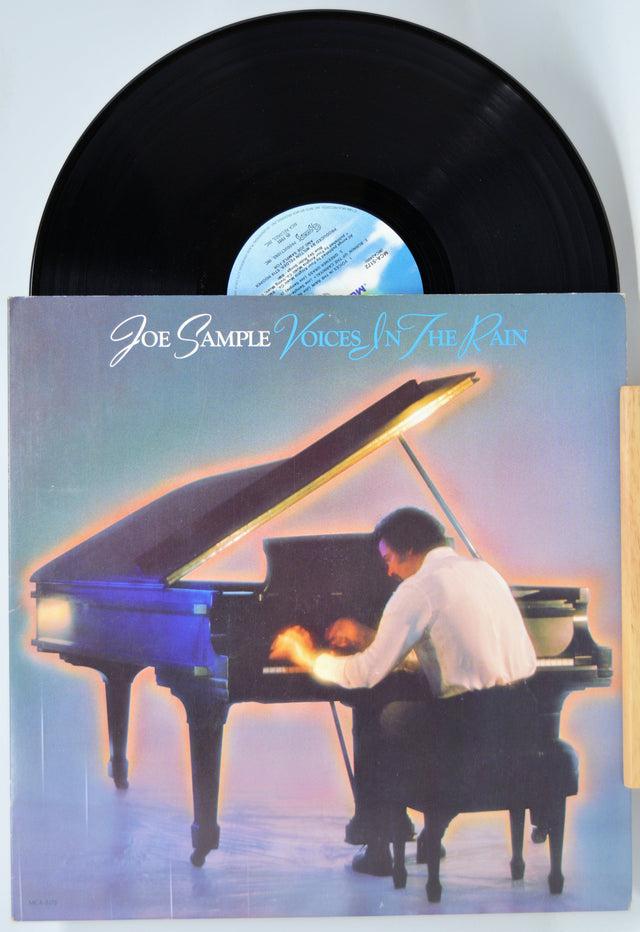 Vinyl record with cover featuring a person playing a piano, titled 'Voices in the Rain' by Joe Sample.