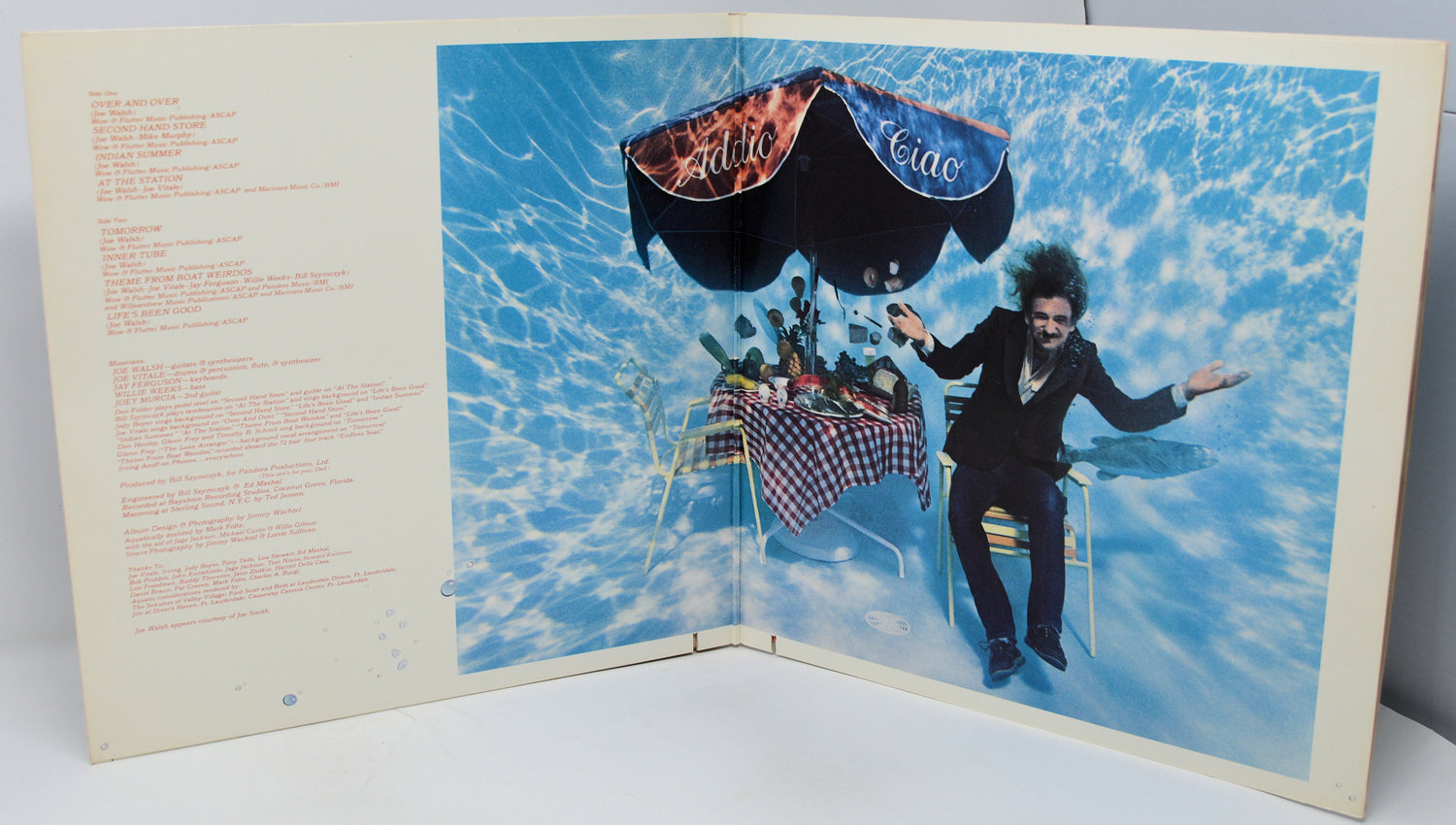 Album cover with a person in a suit and hat, and a parachute, set against a blue sky.