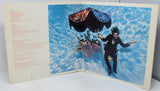 Album cover with a person in a suit and hat, and a parachute, set against a blue sky.