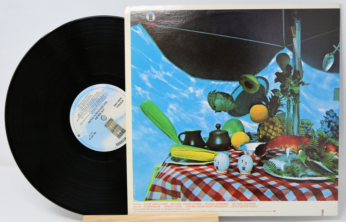 Vinyl record with a colorful cover featuring a table setting and space-themed elements.