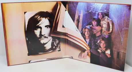 A vintage photo book or album shown open, with printed photographs attached to the pages. The left page features a black-and-white portrait of a man, and the right page shows a group photo in cool blue-purple lighting.