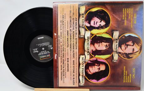 A vinyl record and its printed sleeve for Joe Vitali's 'Rockin' at the Palace' are displayed side by side on a light surface. The black record is partially visible behind the sleeve, which features four circular portrait photos of the performers and track listing text.