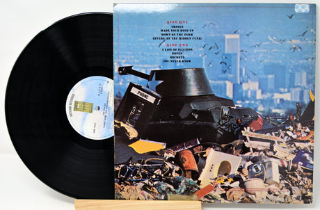 Vinyl record with a colorful album cover featuring a cityscape and debris.