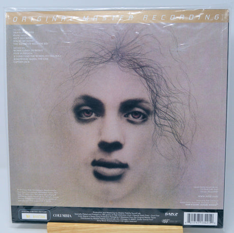 The back cover of a Columbia/Early Records 6-inch vinyl record sleeve for Cyndy Lauper's 'Mastering 6', sealed in its plastic shrink wrap and resting on a wooden display stand.