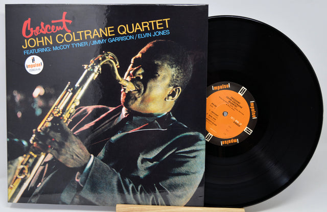 Crescent Records John Coltrane Quartet vinyl LP album with the cover and black record partially pulled out, photographed on a light gray background.