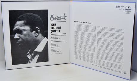 An open book or album program spread showing a black-and-white portrait of John Coltrane on the left page and printed text on the right page, photographed on a white surface.