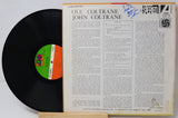 A vinyl record partially pulled from its paper sleeve, showing the black record with a green and orange label next to the printed cover insert for Ole Coltrane's 'Blue Monk' on Atlantic Records.