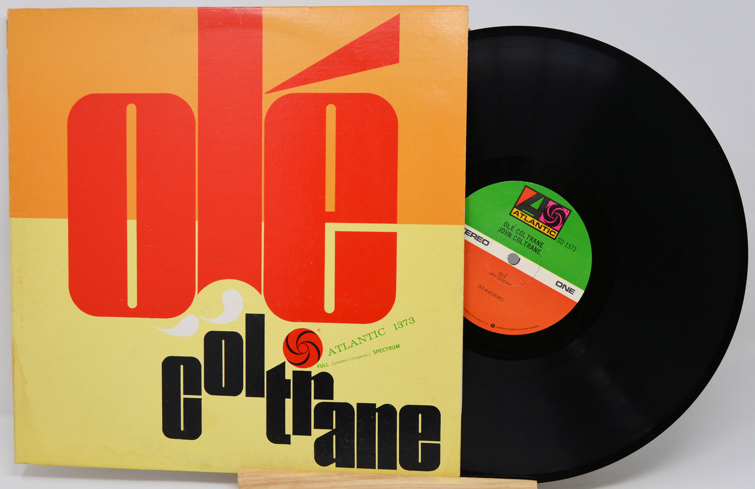 A vinyl record partially pulled from its sleeve, showing the cover art for Ole Coltrane's 'Blue Train' on Atlantic Records. The sleeve features a bold orange and yellow graphic with large red letters spelling 'ole' and black text reading 'col trane'.