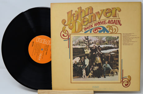Vinyl record and cover of 'Back Home Again' by John Denver on a light gray background