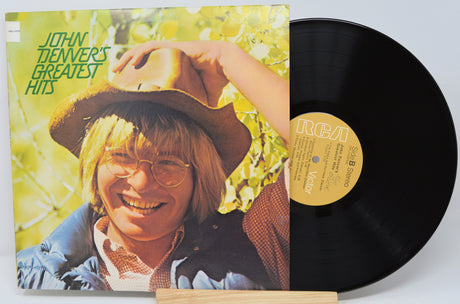 Vinyl record with cover featuring a person wearing a hat and glasses, on a light gray background.