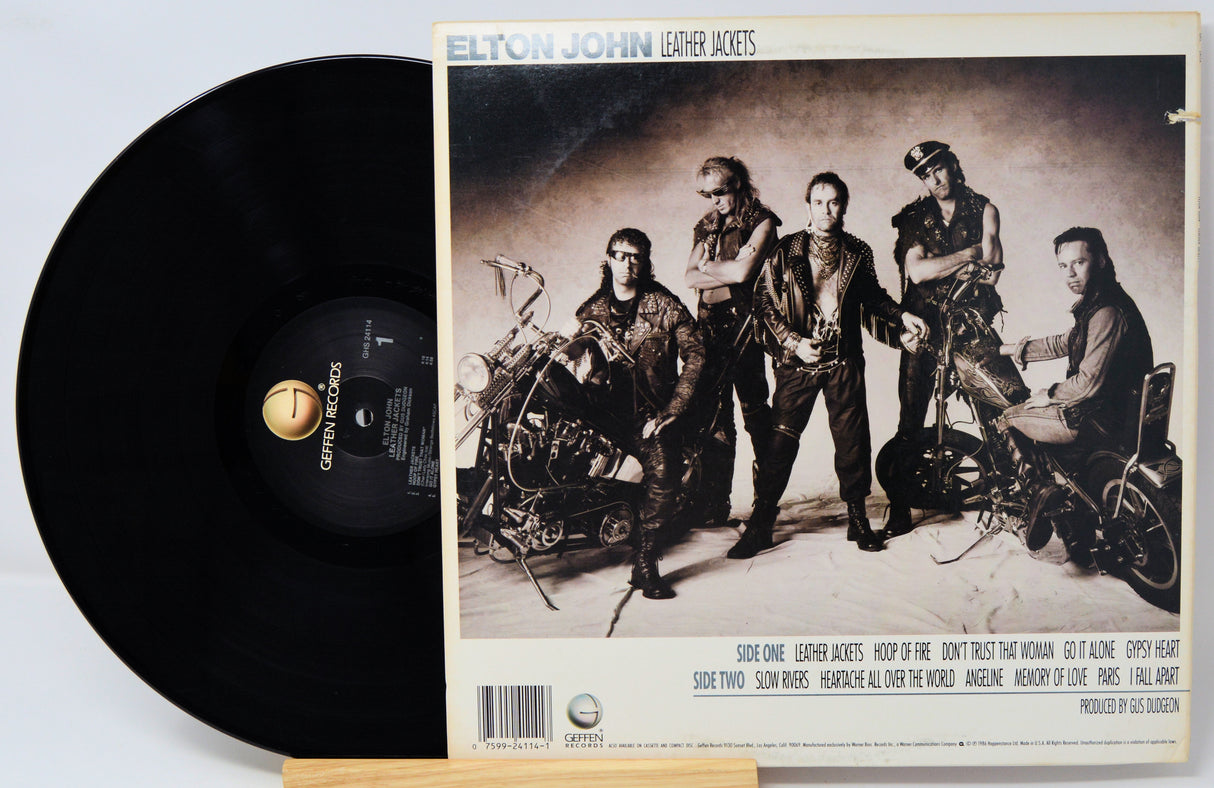 Vinyl record with Elton John 'Leather Jackets' album cover featuring a group of people and motorcycles.