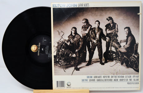 Vinyl record with Elton John 'Leather Jackets' album cover featuring a group of people and motorcycles.