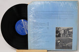 Vinyl record with blue label and cover showing text and images of musicians.