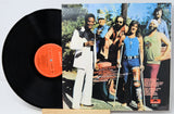 Vinyl record with a colorful album cover featuring a group of people outdoors.