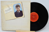 Vinyl record with a cover featuring a young boy's portrait on a light gray background