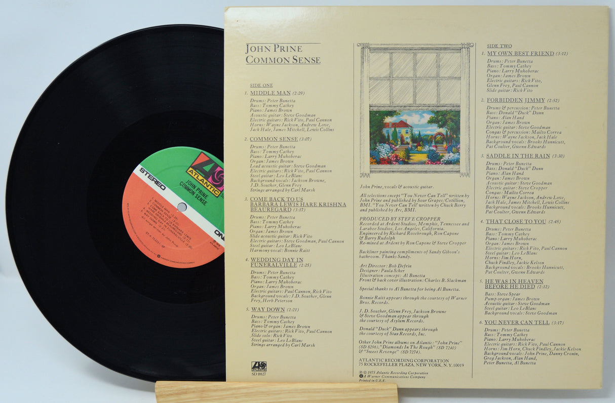 Vinyl record album shown with the black LP partially pulled from the open inner sleeve. The sleeve is cream-colored with printed track listings and a small illustrated cover insert.