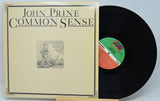 John Prine's 'Common Sense' vinyl record album, showing the beige illustrated cover sleeve alongside the black 12-inch record with a green and orange label.