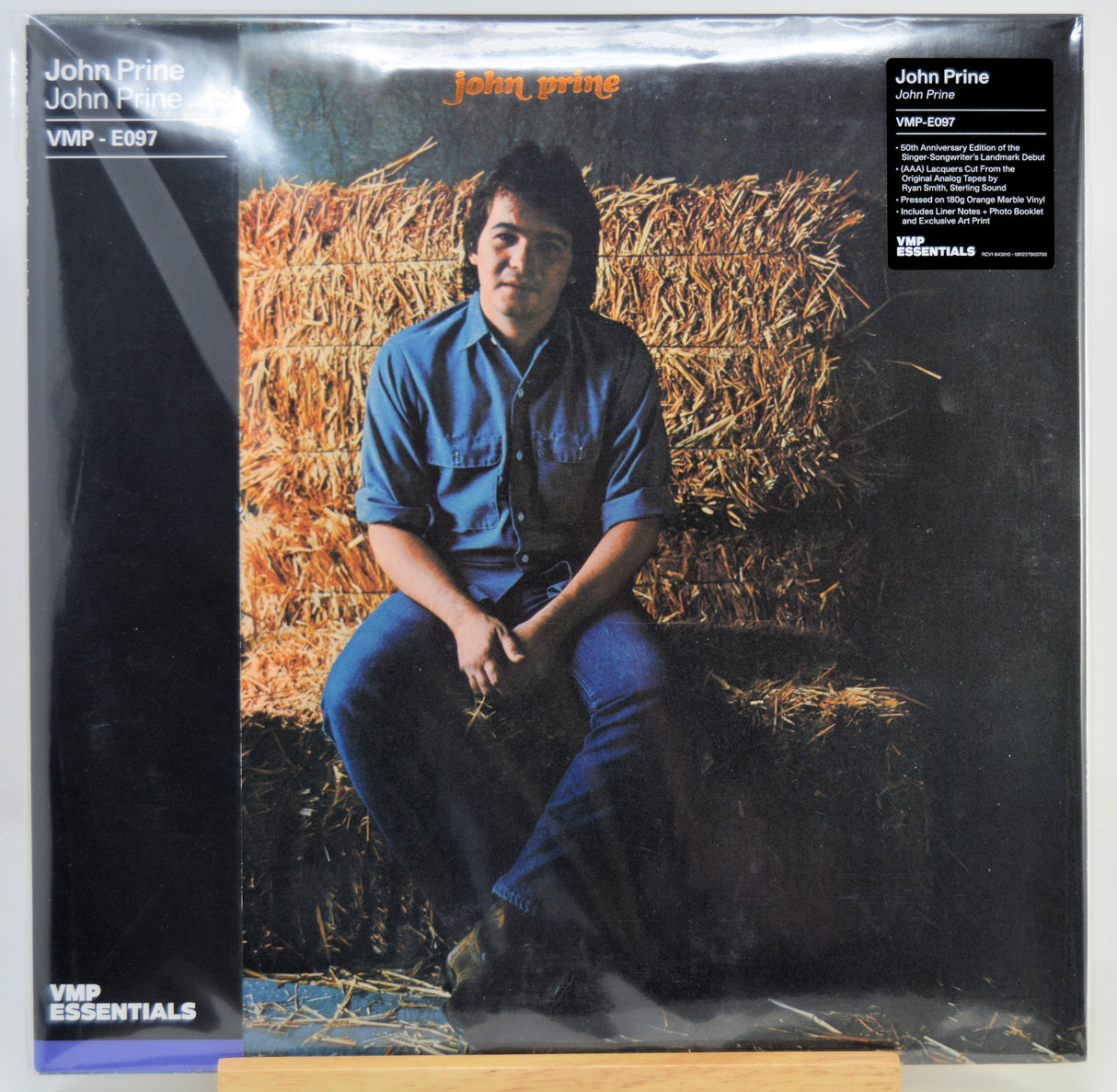 Vinyl record album cover for John Prine's 'John Prine' on VMP Essentials, showing the artist seated in front of hay bales, with black side panels and printed text.