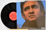 A vinyl record partially pulled from its sleeve, showing the black record and a printed cover with a close-up portrait against a blue background. The center label reads Columbia Stereo.
