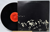Vinyl record with a black and white cover and red label on a light gray background
