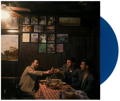 Three men sitting at a table in a dimly lit room with framed pictures on the wall.