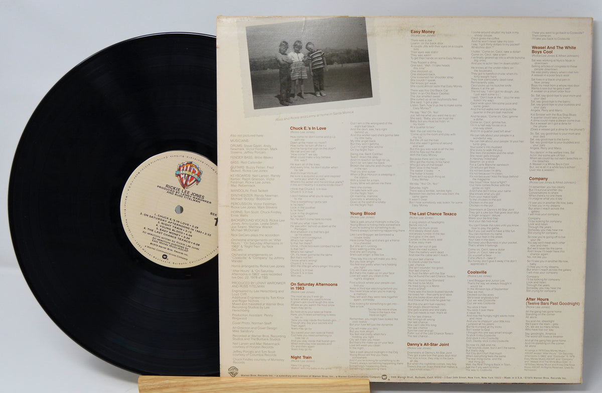 Vinyl record with cover displaying track listing and photo of three people.