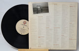 Vinyl record with cover displaying track listing and photo of three people.
