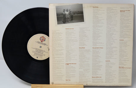 Vinyl record with cover displaying track listing and photo of three people.