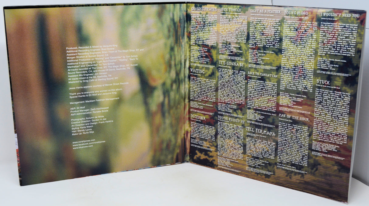 An open printed booklet or album-style book spread on a white surface, showing two printed pages with blurred forest imagery and dense text blocks. No person or real environment is present beyond the tabletop, so this is Product/Packaging rather than Lifestyle.