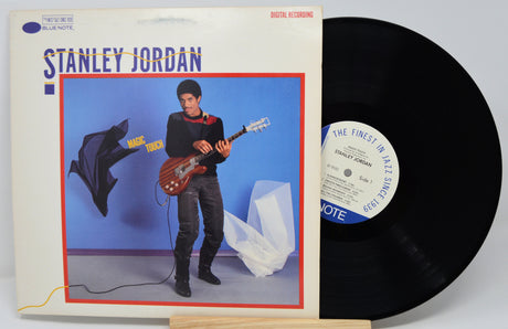Vinyl record with cover featuring a person playing guitar against a blue wall.
