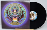 Journey 'Captured' vinyl record LP with the album cover sleeve and a black record partially pulled out, displayed on a small wooden stand against a light gray background.
