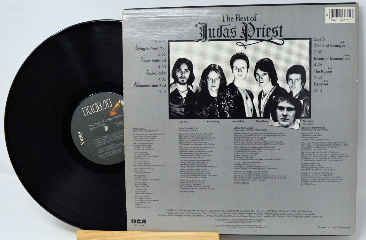 Vinyl record package showing the black LP disc partially pulled from the back cover of 'The Best of Judas Priest' on a white background.
