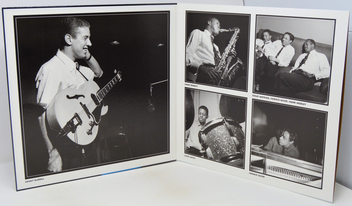 An open printed album or photo book showing black-and-white photographs of a musician performing, photographed on a white surface against a white background.