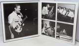 An open printed album or photo book showing black-and-white photographs of a musician performing, photographed on a white surface against a white background.
