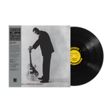 Vinyl record with a yellow label and a black and white album cover of a man playing guitar.