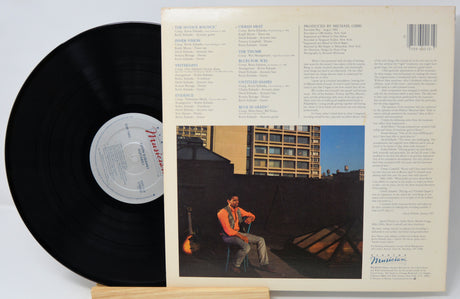 Vinyl record with cover featuring a person on a rooftop and building in the background