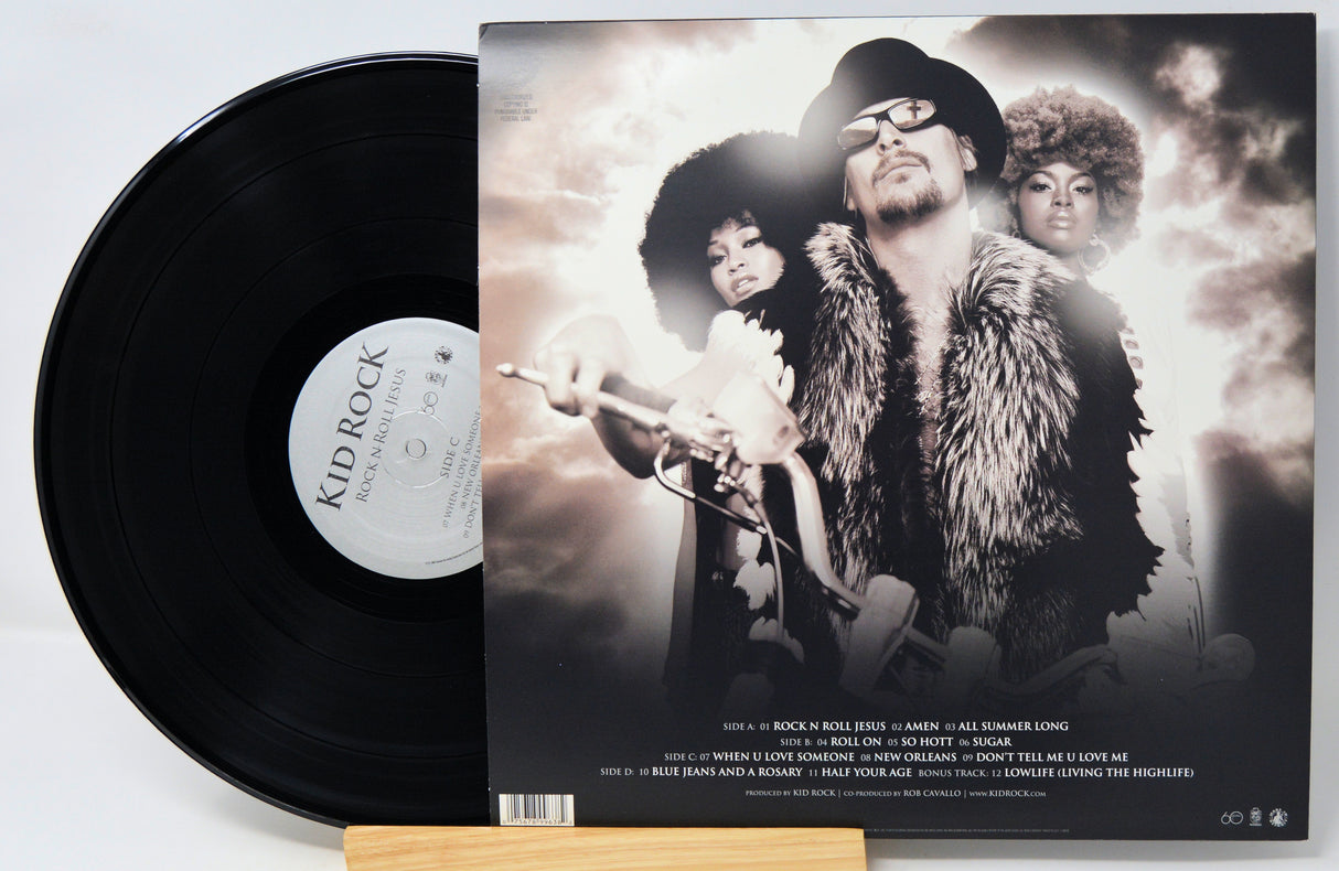 A vinyl record partially pulled from its sleeve, showing the black record on the left and the printed album cover on the right. The cover features a sepia-toned portrait of three people, with the text 'KID ROCK' visible on the record label.