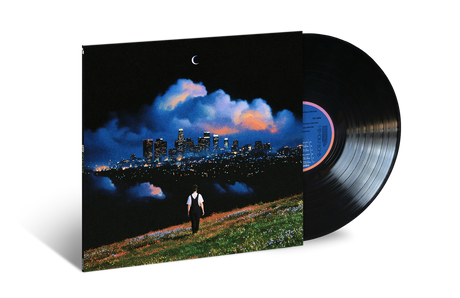 Vinyl record album with a square jacket showing a night cityscape and a lone figure on a grassy hill, alongside a partially visible black vinyl record on a white background.