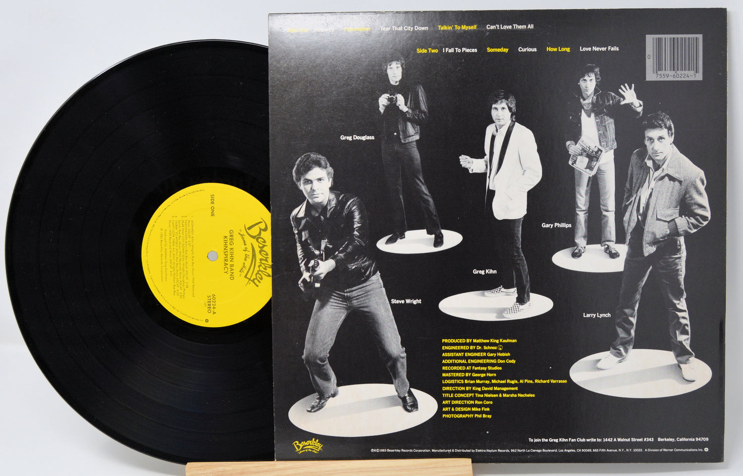 Vinyl record titeled Kihnspiracy with a yellow label and album cover featuring band members on white stands.