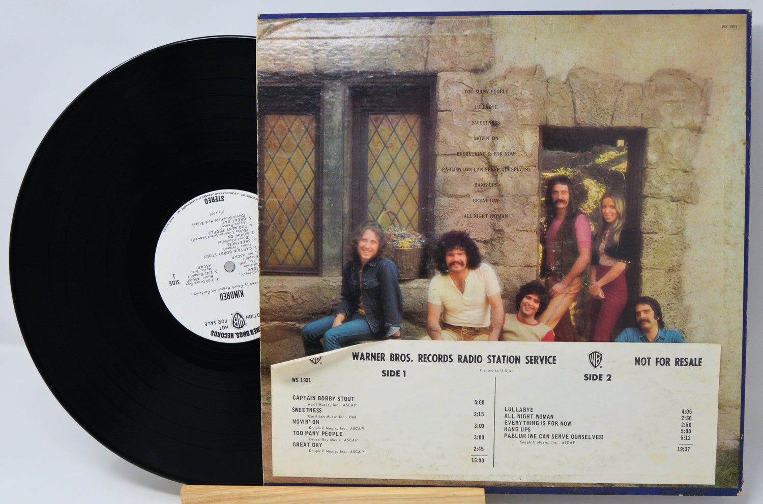 Vinyl record with cover featuring a group of people in front of a stone building.