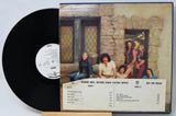 Vinyl record with cover featuring a group of people in front of a stone building.