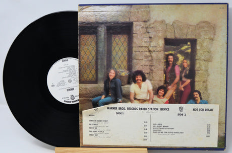 Vinyl record with cover featuring a group of people in front of a stone building.