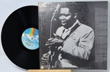Vinyl record with a cover featuring a musician holding a guitar on a light blue background