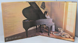 Album cover with a woman playing a piano and a cat sitting next to her.